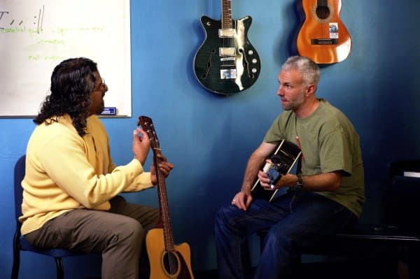 Guitar teacher explains music concept to student.