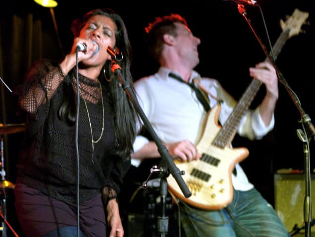 A singer and electric guitar player perform onstage.