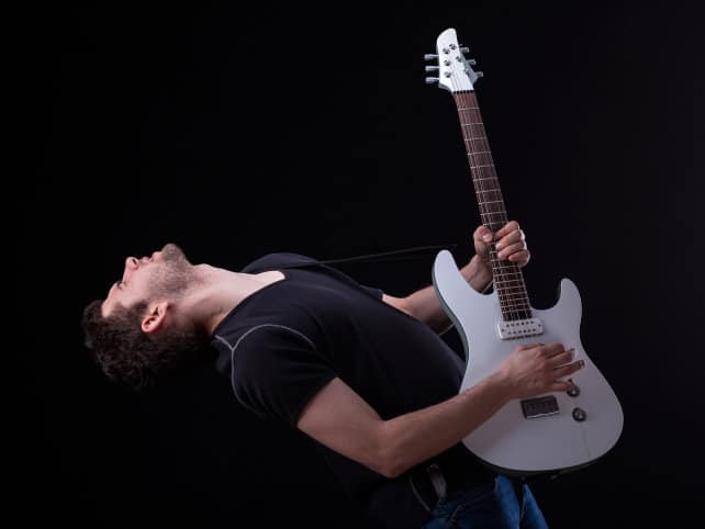 Guitar player arches backwards dramatically.