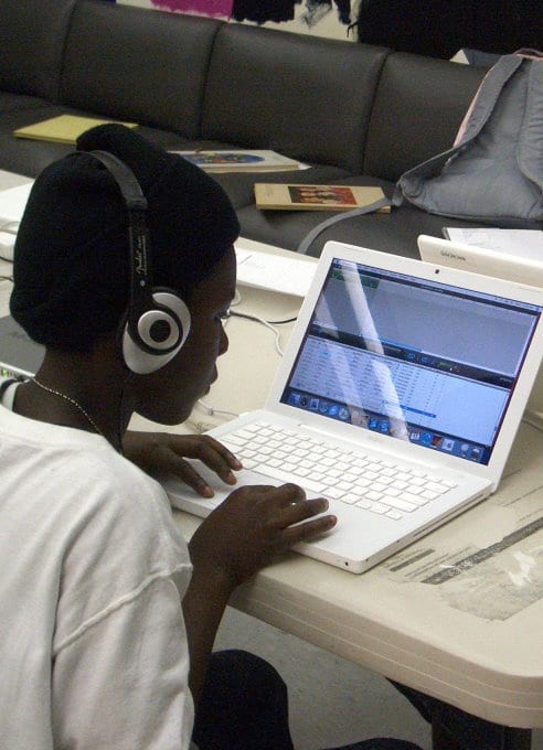 A student with headphones on uses music software on a laptop.
