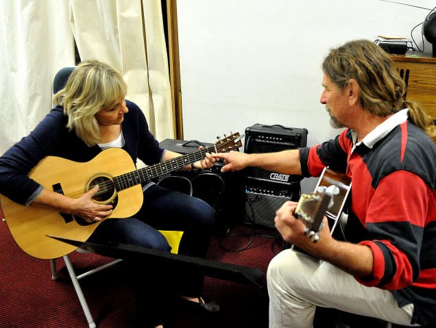 Guitar teacher shows new chord to student.